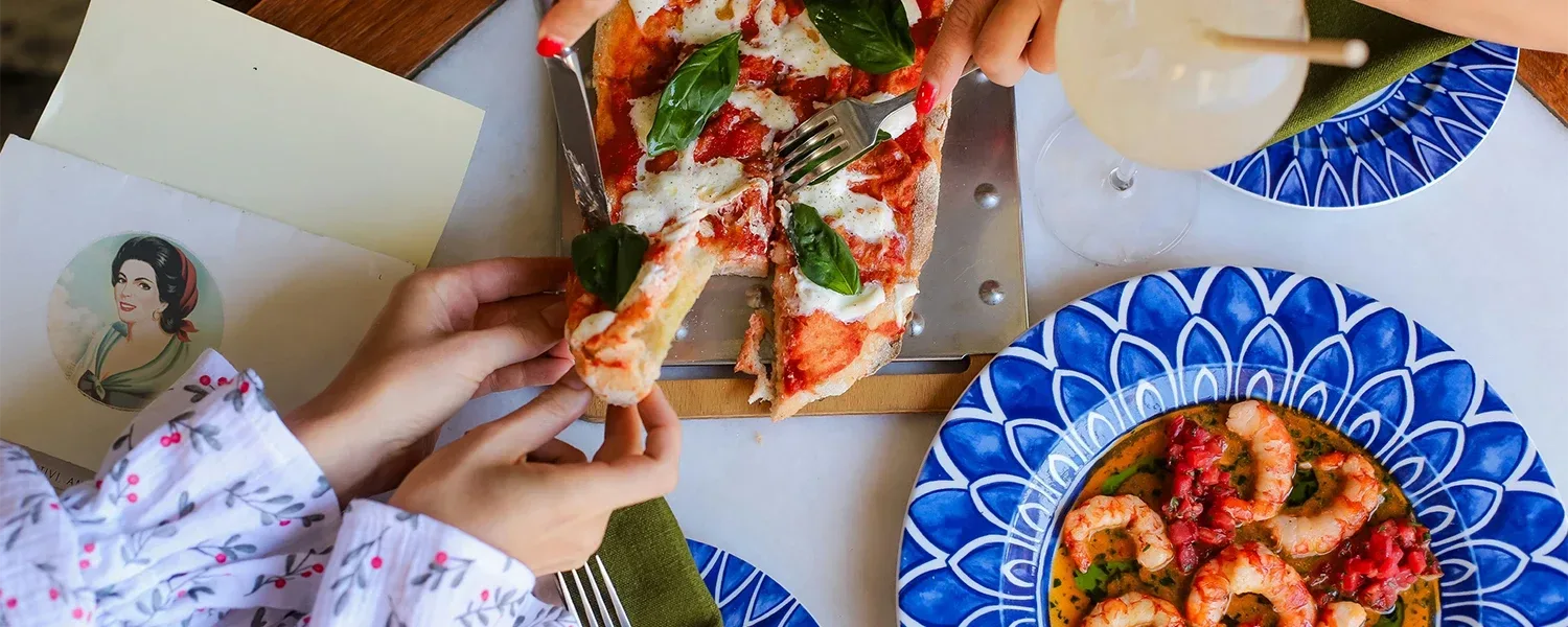Homemade pizza and plate of saucy shrimp from above.