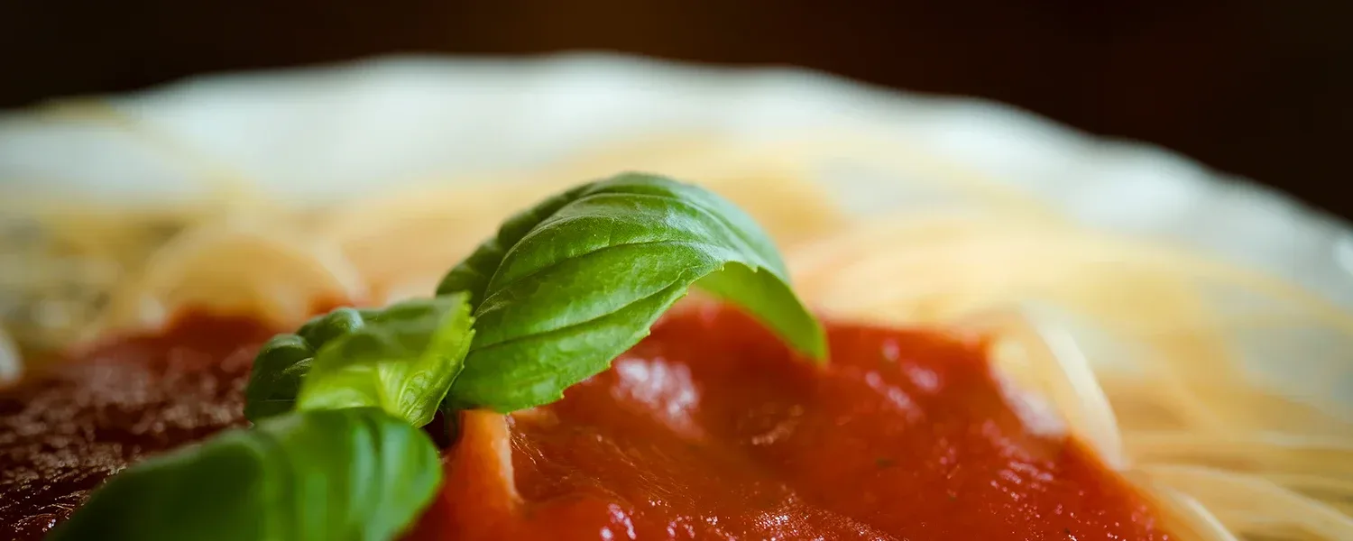 Bowl of spaghetti with red sauce and fresh basil.