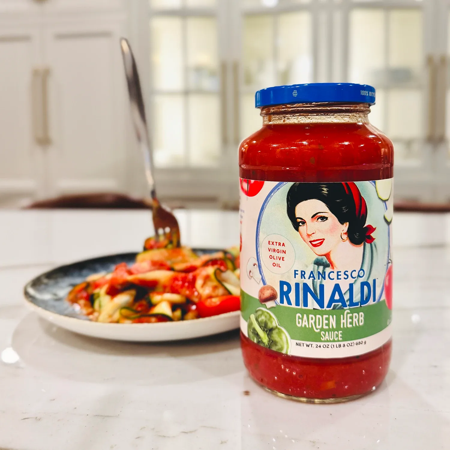 Jar of Francesco Rinaldi Garden Herb sauce and plate of zoodles in kitchen.