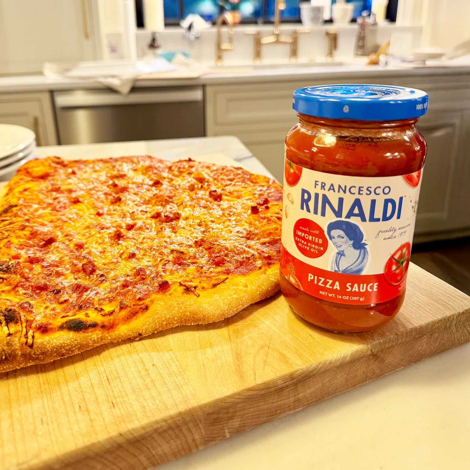 Homemade pizza on cutting board with Francesco Rinaldi pizza sauce jar.
