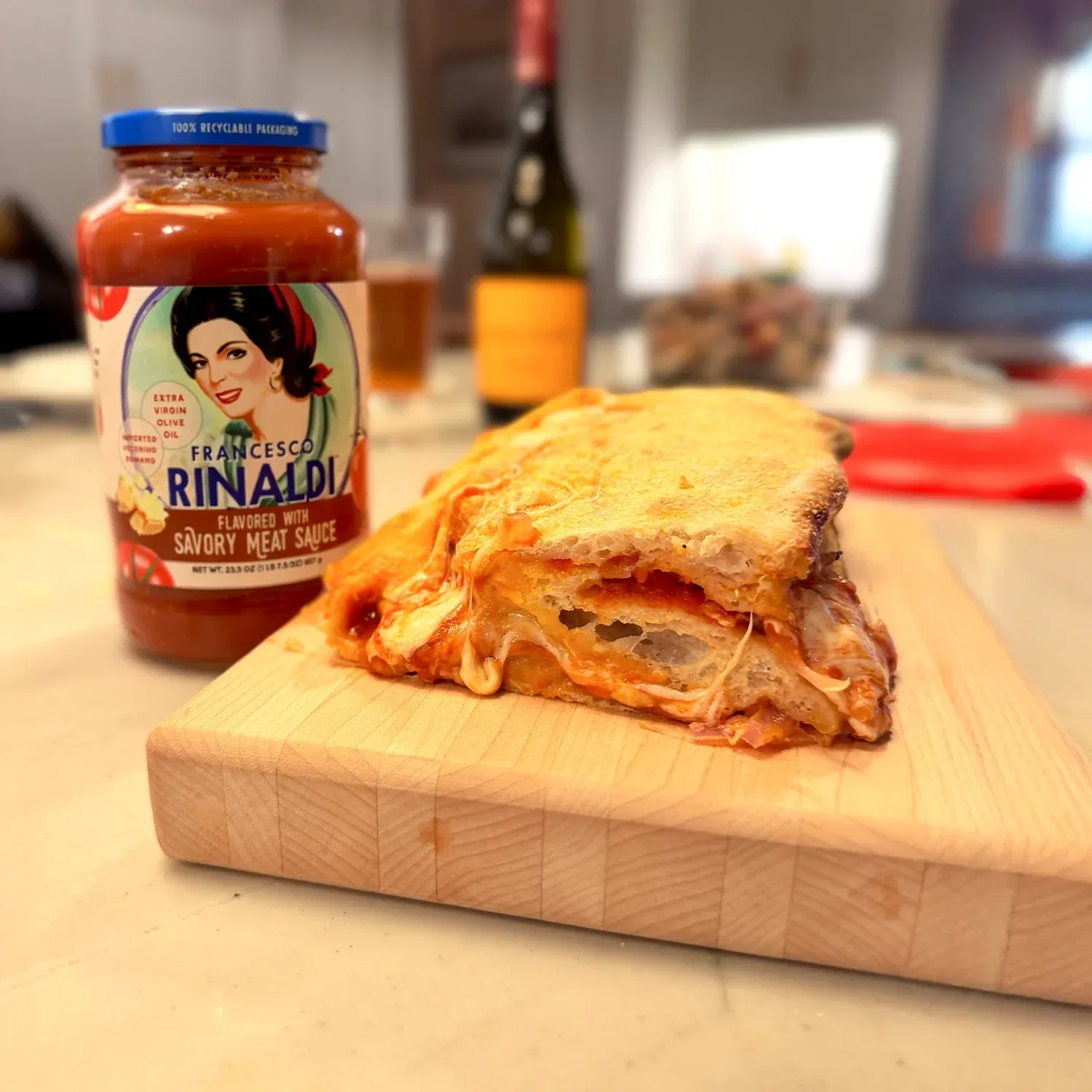 Stromboli sandwich next to a jar of sauce on a cutting board.